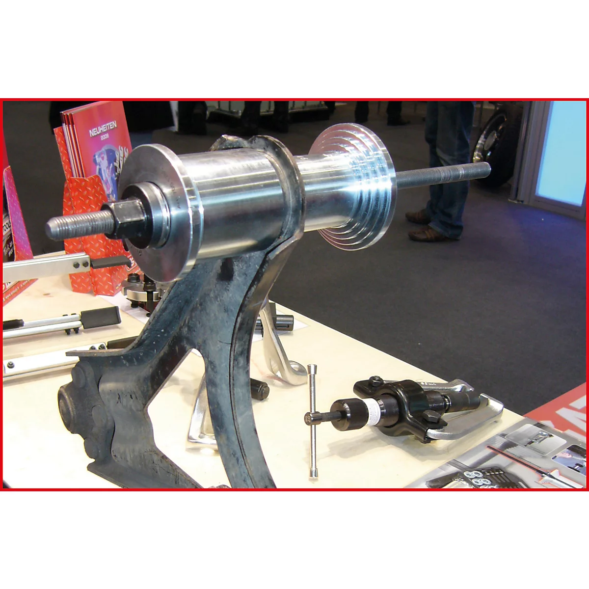 Ein Werkzeug zur Reparatur eines Fahrzeugs, das auf einem Tisch steht. In der Mitte befindet sich ein silberner Zylinder, der von einer schwarzen Halterung getragen wird.